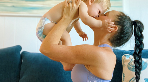 Five pregnant women standing next to each other wearing a Shefit Ultimate Sports Bras, one holding a baby. 