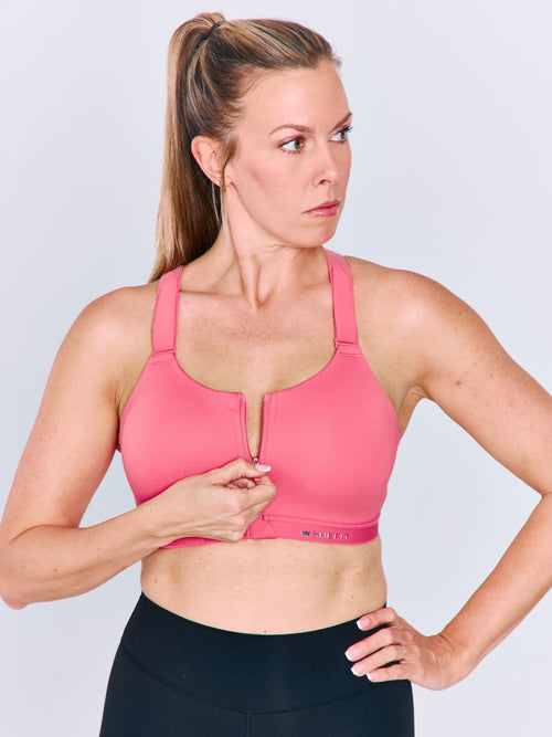 A woman wearing a bright pink Emerge Sports Brawith a front zipper and black athletic bottoms, shown against a light gray studio background.