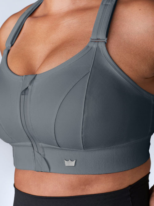 Close-up of a gray SHEFIT sports bra with a front zipper and adjustable straps.