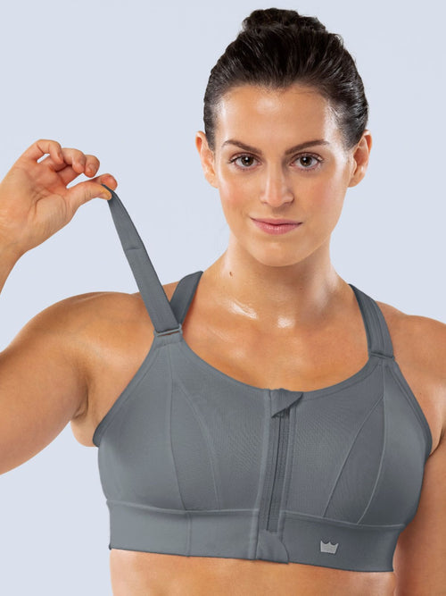 Woman demonstrating the adjustable shoulder strap of a gray SHEFIT sports bra.