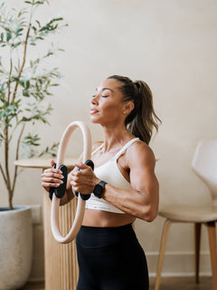 Women wearing Ivory Emerge Sports Bra. Women is working out with work out equipment.